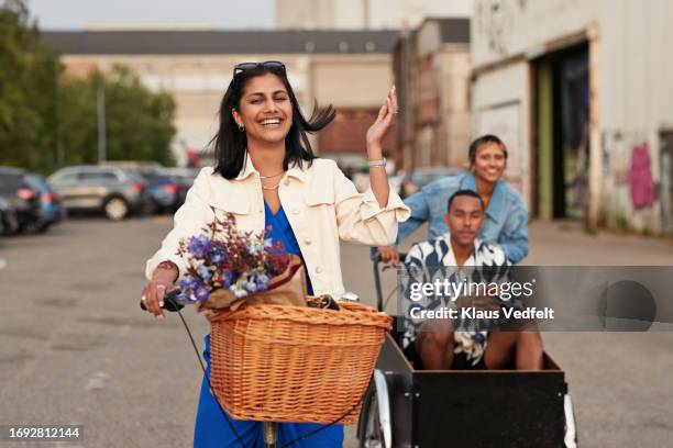 happy young woman riding bicycle by friends - bicycle flowers stockfoto's en -beelden