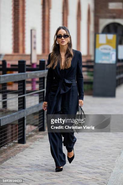 Tamara Kalinic wears navy jacket, silver Alaia bag, pants, pointed heels, Bottega Veneta earrings, sunglasses outside Alberta Ferretti during the...