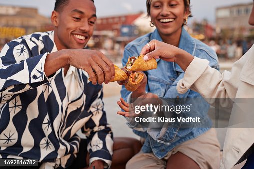 Multiracial friends toasting tacos on promenade