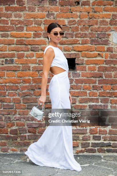 Guest wears white cut out dress, silver bag outside Alberta Ferretti during the Milan Fashion Week - Womenswear Spring/Summer 2024 on September 20,...