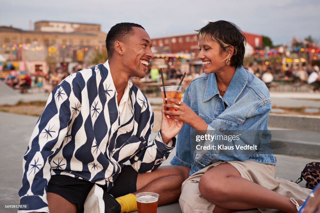 Happy heterosexual couple holding drink glass on promenade