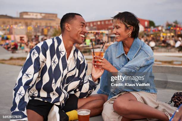 happy heterosexual couple holding drink glass on promenade - real wife sharing 個照片及圖片檔