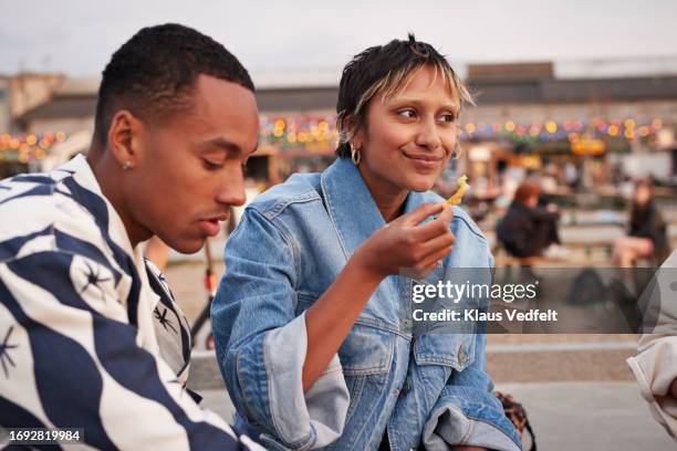 smiling young woman having food by male friend - crisps foto e immagini stock