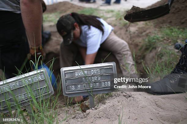 An anthropology student digs to reach the remains of suspected undocumented immigrants while exhuming bodies from a gravesite on May 22, 2013 in...