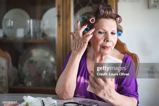 woman putting on makeup - hair curlers stock-fotos und bilder