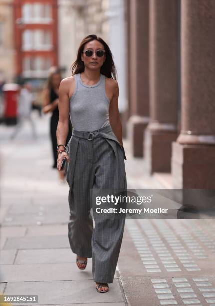 Guest is seen outside Molly Goddard show wearing see through sunnies, grey tank top, grey striped suit pants and animal print heels during London...