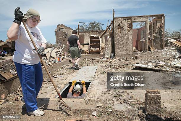 Lean Newbury cleans debris from around her late father's home as Dean Dye, a friend of her father's, looks over a storm shelter he had installed at...