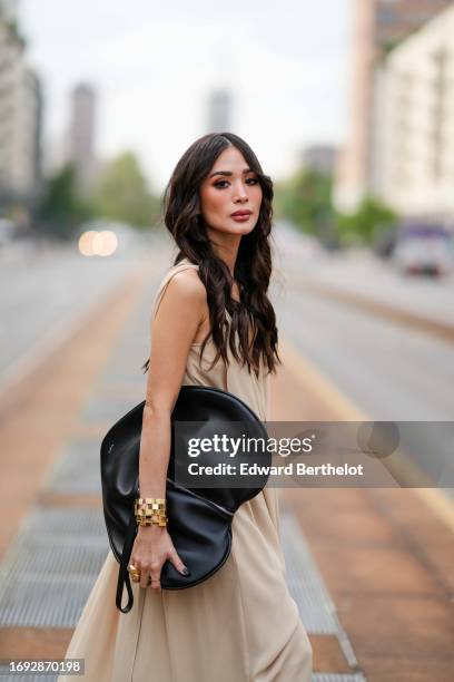 Heart Evangelista wears a beige flowing gathered low-neck v-neck long dress from Onitsuka Tiger, a golden bracelet, a heart shaped Alaia oversized...