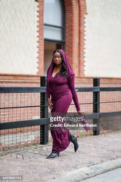 Coco Bassey wears a purple long scarf over the head, a low-neck long maxi flowing dress, outside Alberta Ferretti, during the Milan Fashion Week -...