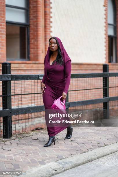 Coco Bassey wears a purple long scarf over the head, a low-neck long maxi flowing dress, outside Alberta Ferretti, during the Milan Fashion Week -...