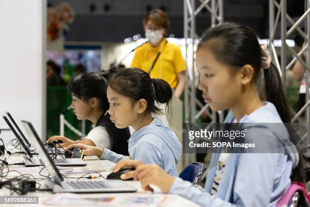 Participants of a video game programming workshop for kids solve an assigned programming task on distributed laptops inside the family and kids...