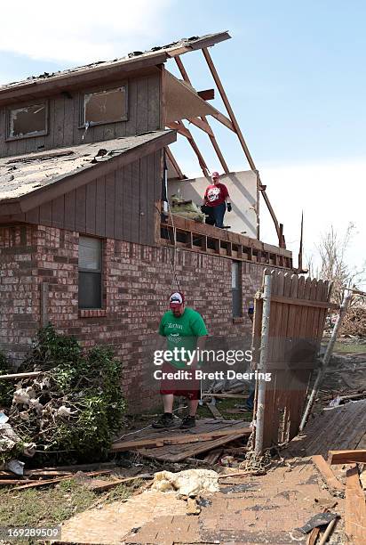 Danny Grover walks beside his house as his mother Ann stands upstairs during cleanup after the tornado May 22, 2013 in Moore, Oklahoma. The...