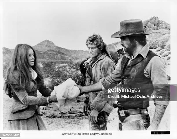 Sarah Miles and Burt Reynolds making exchange while Bo Hopkins watches in a scene from the film 'The Man Who Loved Cat Dancing', 1973.