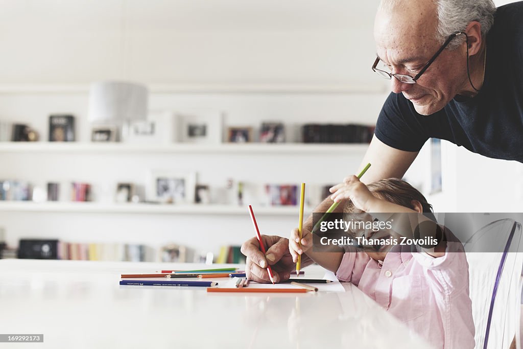 Grandfather help his grandson with drawing