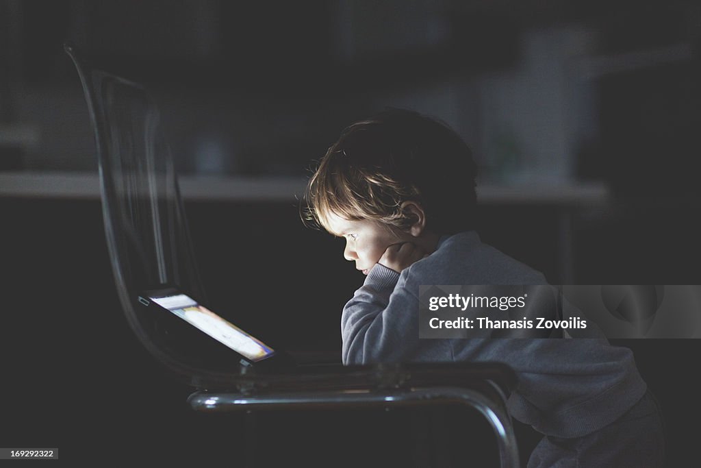 Small boy looking at a tablet in the dark