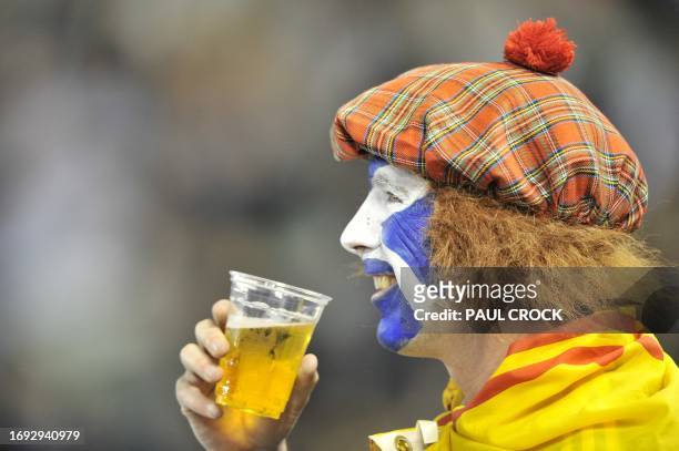 Scottish tennis fan with his face painted in the colours of the Scottish flag drinks beer as he watches Scot Andy Murray of Britain beat David Ferrer...
