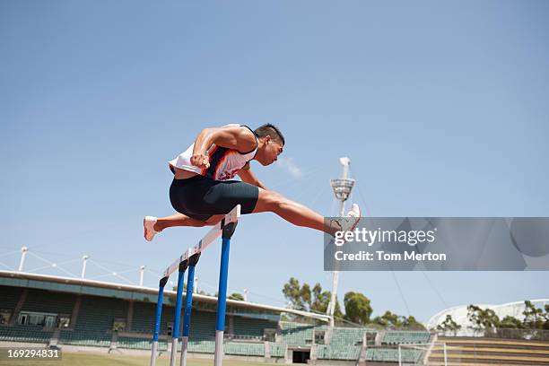 runner jumping hurdles on track - hordelopen atletiekonderdeel stockfoto's en -beelden