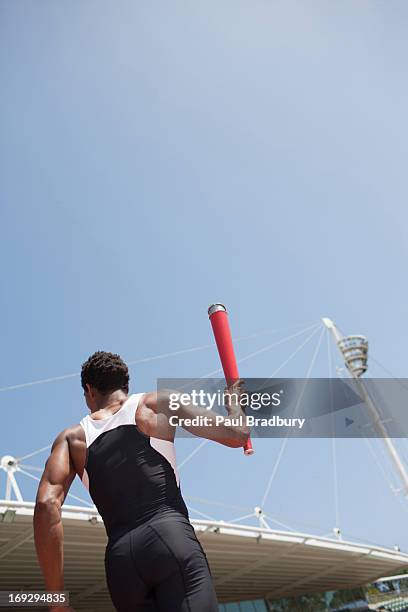 runner running with torch on track - men's track stockfoto's en -beelden