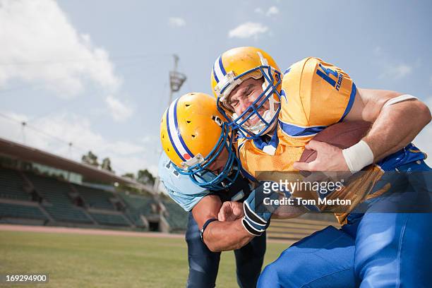 football players playing football - tackling stock pictures, royalty-free photos & images