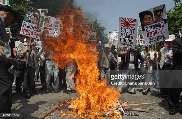 South Korean protesters burn portraits of Japanese Prime Minister Shinzo Abe and Osaka Mayor Toru Hashimo during a rally on May 23, 2013 in Seoul,...