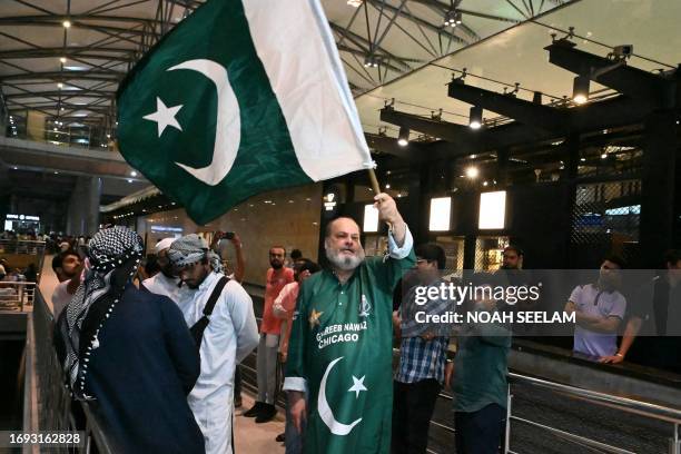 Pakistan cricket fan waves a flag of Pakistan as he waits for the arrival of Pakistan's cricket team at the Rajiv Gandhi International Airport in...