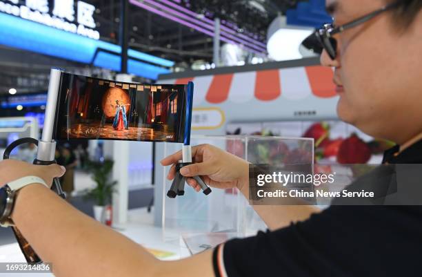 Staff member shows flexible display screen during the 2023 World Manufacturing Convention at Hefei Binhu International Convention and Exhibition...
