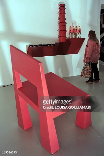 Visitor looks at a 'shelve' by Hain Steinback next to a chair by Alessandro Mendini arranged by architect Andreas Angelidakis from the collections of...