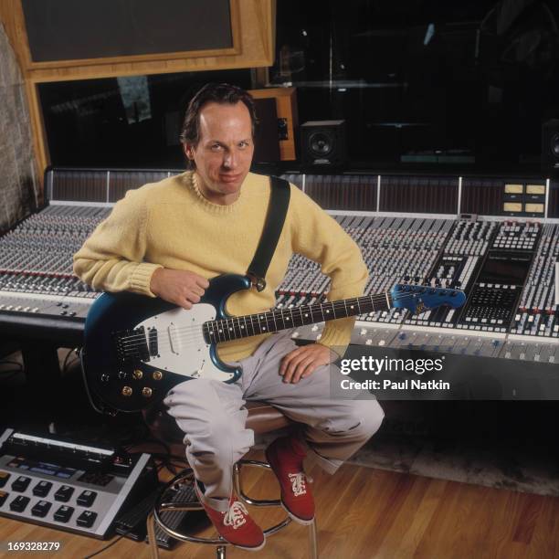 Portrait of musician Adrian Belew as he sits on an amplifier with a guitar on his lap, Lake Geneva, Wisconsin, April 15, 1994.