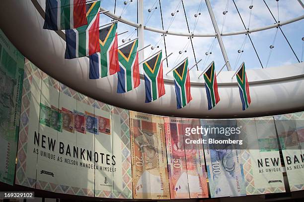 South African national flags hang above an advertisement for the new Mandela rand banknotes at the headquarters of the central bank in Pretoria,...