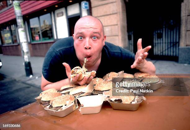 Portrait of British singer Buster Bloodvessel , of the ska group Bad Manners, as he sits at an outdoor table full of hamburgers, Chicago, Illinois,...