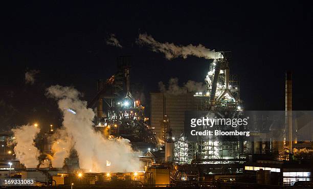 Buildings are seen illuminated as vapor rises from cooling towers at the steel works operated by Tata Steel Ltd. In Port Talbot, U.K. On Wednesday,...