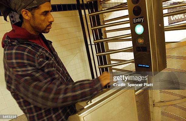 Man swipes his Metrocard at a subway station toll booth December 18, 2002 in New York City. With the threat of a transit strike over, the...