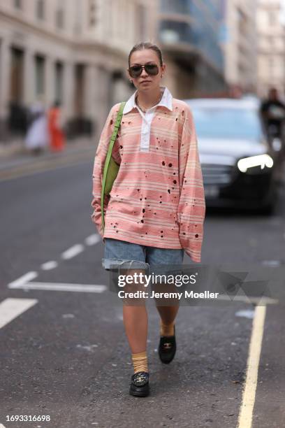 Guest is seen outside Molly Goddard show wearing black aviator sunnies, orange and distressed colored shirt, short distressed denim shorts, yellow...