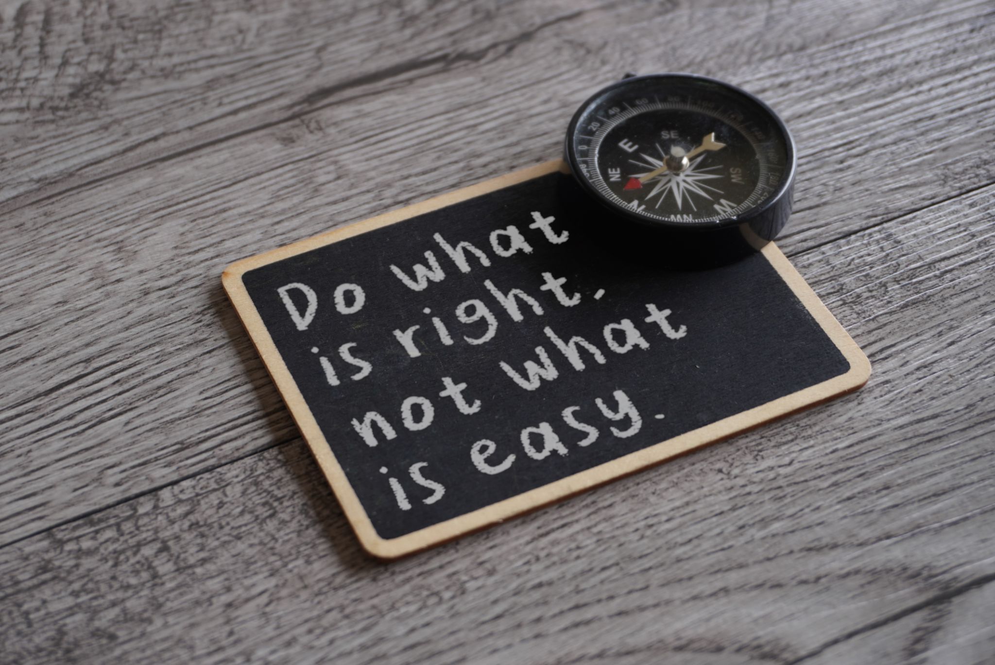 Closeup image of chalkboard with text DO WHAT IS RIGHT, NOT WHAT IS EASY and compass. Closeup image of chalkboard with text DO WHAT IS RIGHT, NOT WHAT IS EASY and compass.