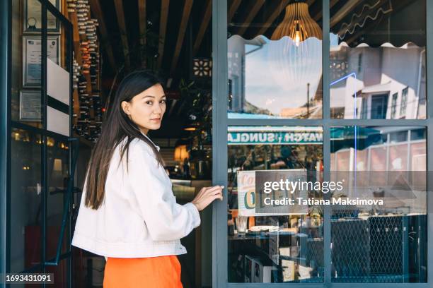 young asian woman enters a cafe with an open sign. - entering restaurant stock pictures, royalty-free photos & images