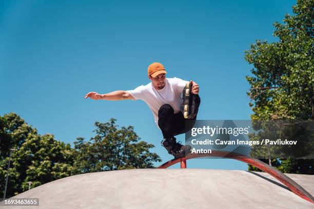 aggressive roller skater performing a trick on a railing in skatepark - trick rollerblades stock pictures, royalty-free photos & images