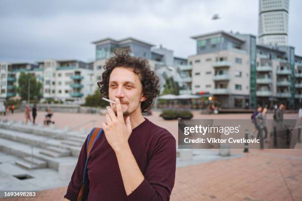 portrait of a men smoking a cigarette in the city - ongezond leven stockfoto's en -beelden