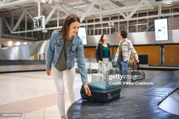 mulheres à espera de bagagem da esteira transportadora no terminal do aeroporto - área de retirada de bagagem - fotografias e filmes do acervo