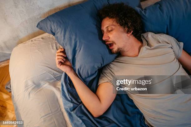 giovane che russava nel letto di notte - bocca aperta foto e immagini stock
