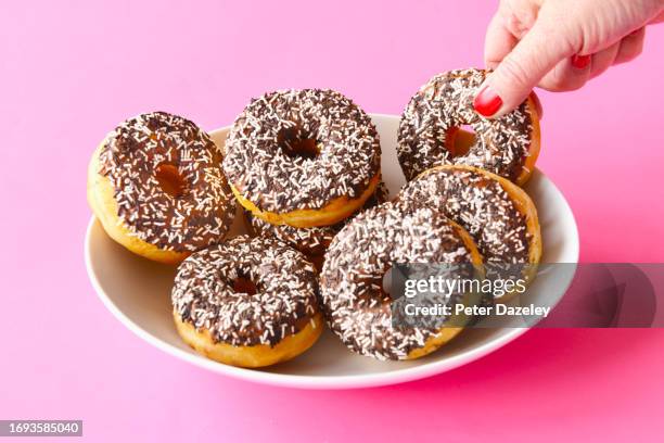 woman taking donut - transfettsäure stock-fotos und bilder