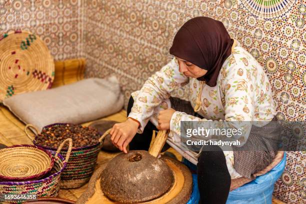 femme marocaine produisant de l’huile d’argan par des méthodes traditionnelles - arganier photos et images de collection