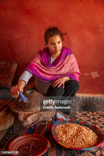 moroccan woman producing argan oil by traditional methods - argan oil production in morocco stock pictures, royalty-free photos & images