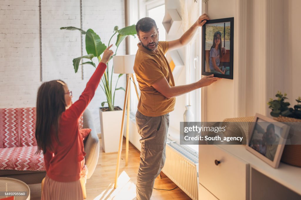 Father and daughter choosing where to put picture on the wall