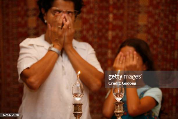 Mother and daughter lighting Shabbat candles and praying