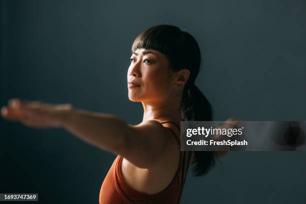 asian woman in a yoga class - mature woman yoga indoors stock pictures, royalty-free photos & images
