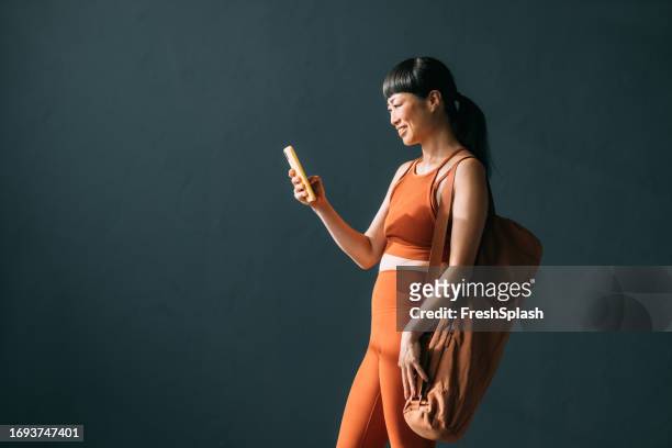 wellness on the go: japanese woman stands, smiles, and uses yoga app - set sport bildbanksfoton och bilder