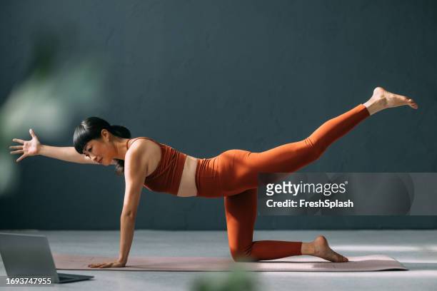focused yoga practice: happy japanese woman with laptop following an online class - set sport bildbanksfoton och bilder