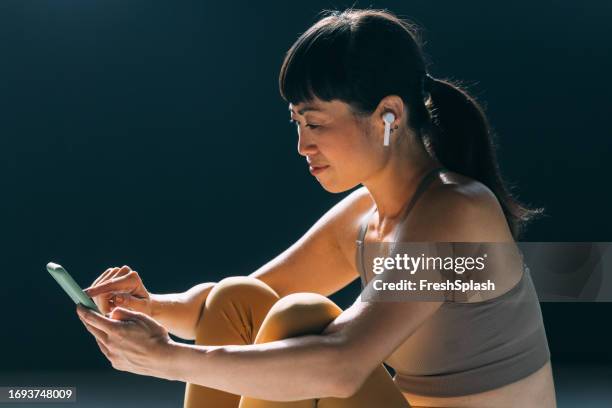 mindful moments: japanese woman finds peace on her mat with earphones and phone - woman headphones sport smile iphone stock pictures, royalty-free photos & images