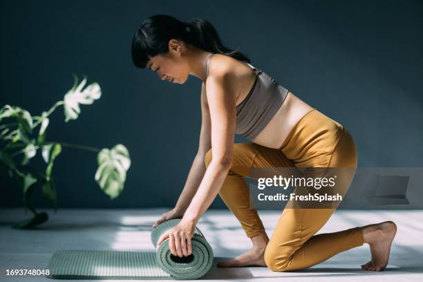 preparation for exercise: unrolling the yoga mat - rolled up yoga mat stock pictures, royalty-free photos & images