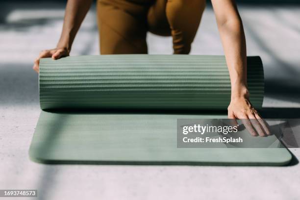 preparation for exercise: woman unrolling the yoga mat - mat stock pictures, royalty-free photos & images